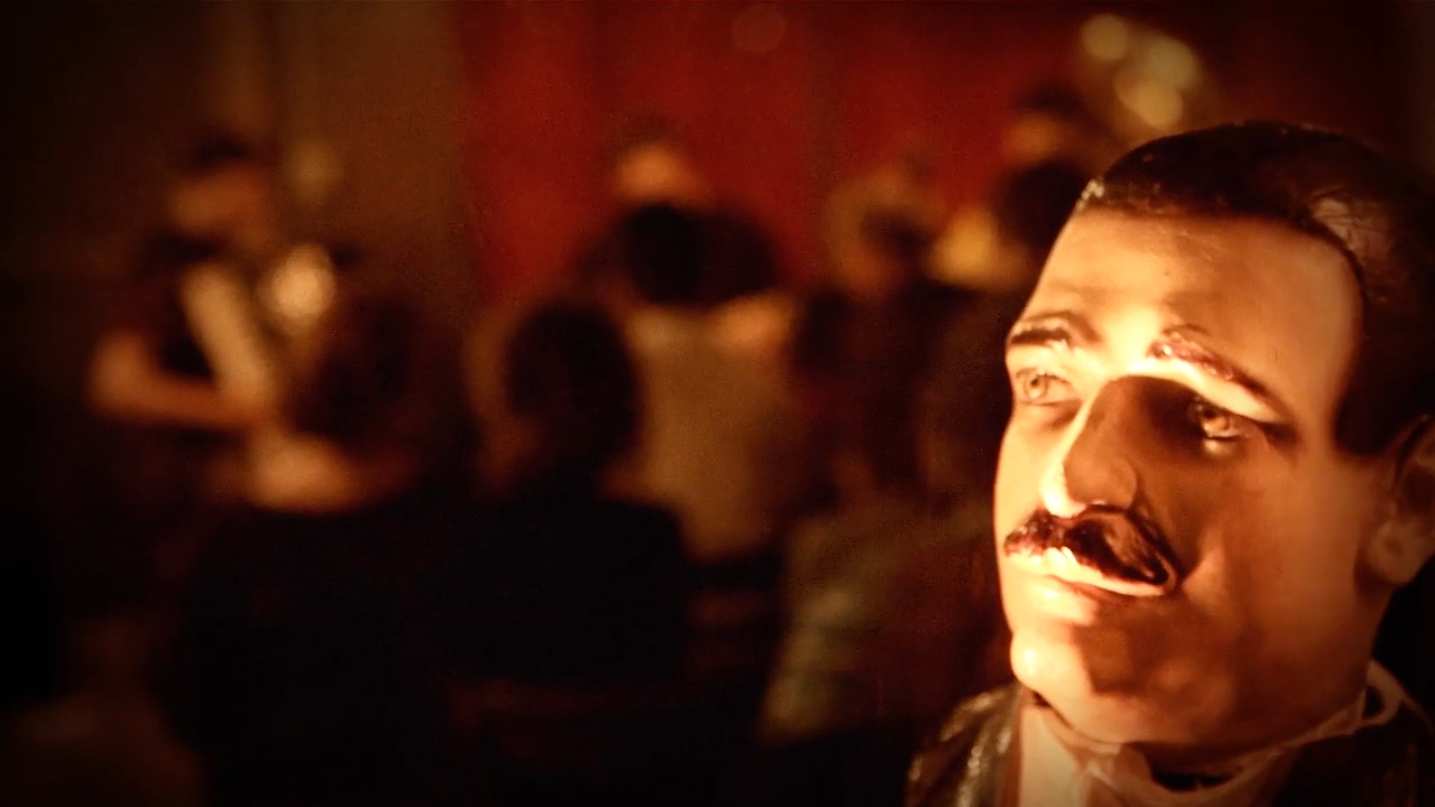 Head of a realistic male sculpture bust from the 1930s lit eerily from below with trio band out of focus in the background with red curtain behind